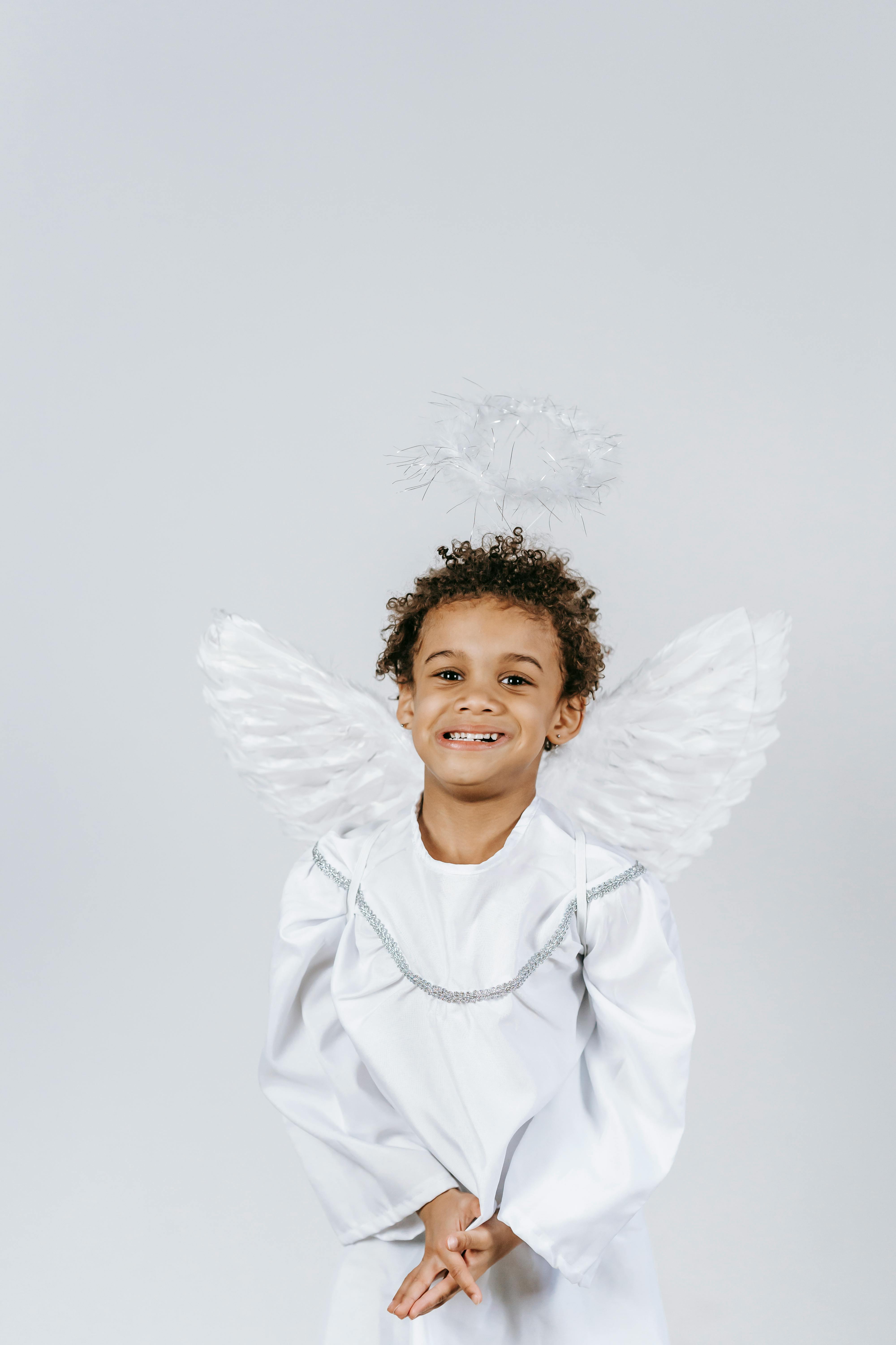 Cute black boy in angel outfit in studio during holiday · Free Stock Photo
