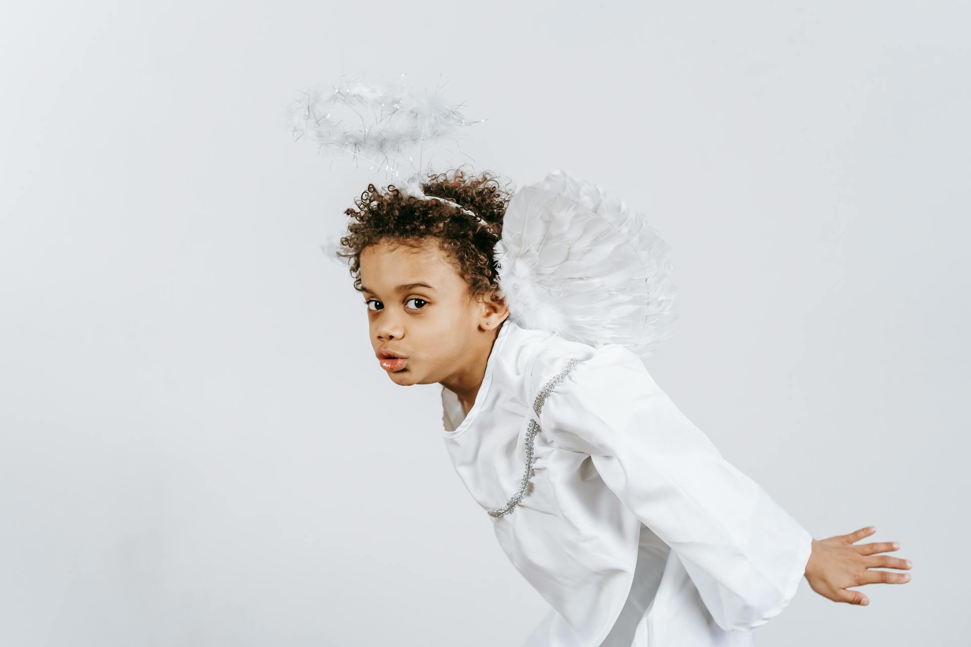 Cheerful black boy in angel costume during festive event