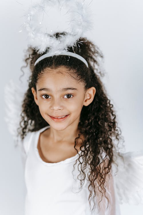 Cute black girl in costume of angel with soft nimbus