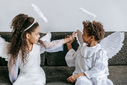 Free Adorable little African American children in costumes of white angels with wings playing with each other Stock Photo