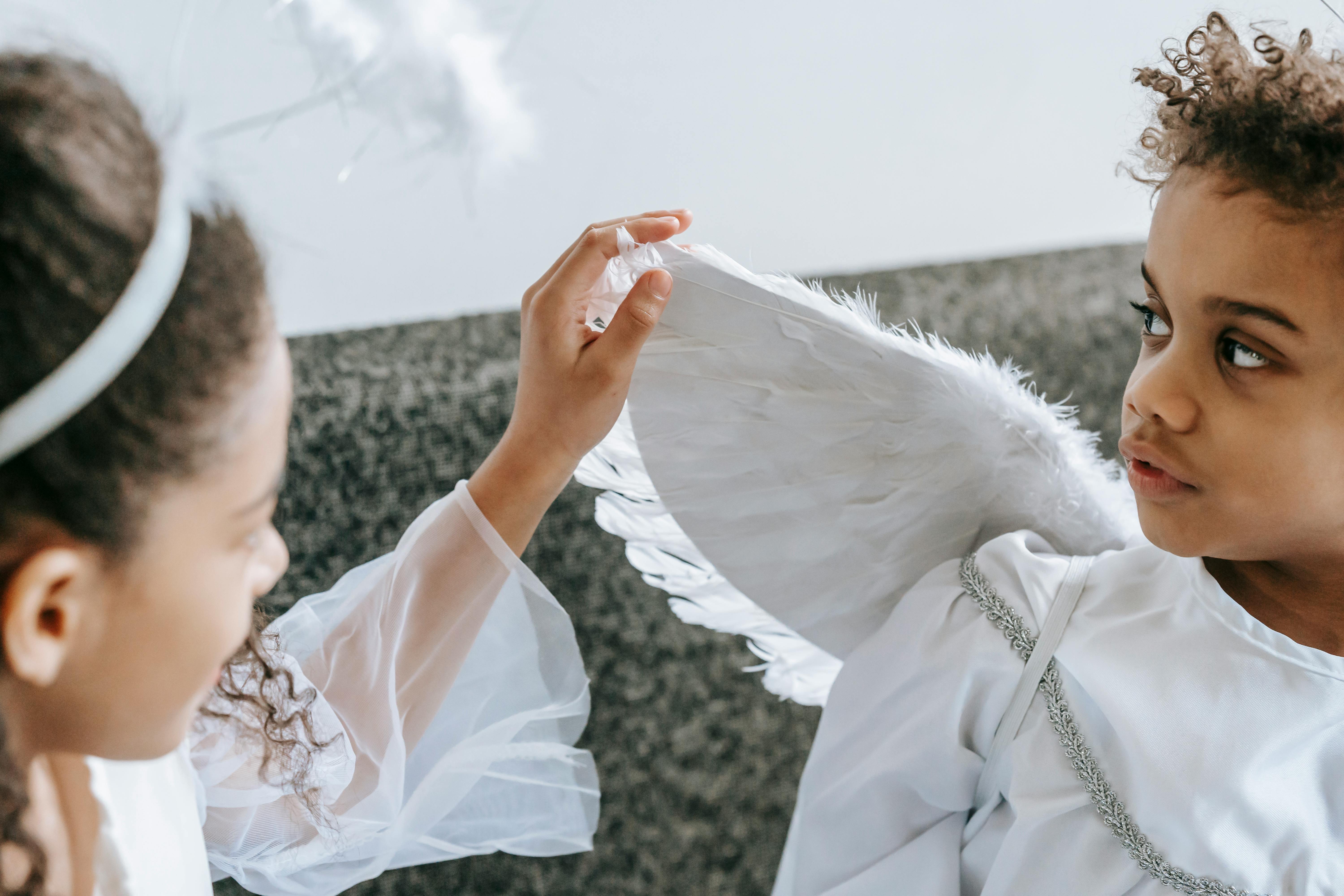 black girl touching wing of angel costume of brother