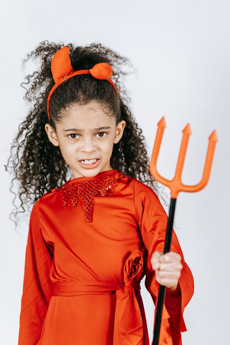 Cute Little Black Girl In Devil Costume With Pitchfork In Hand Looking At Camera