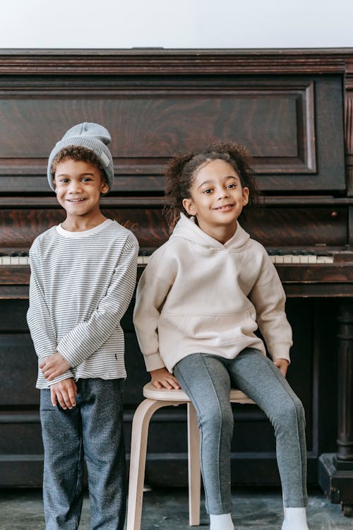 Happy little ethnic children near piano at home