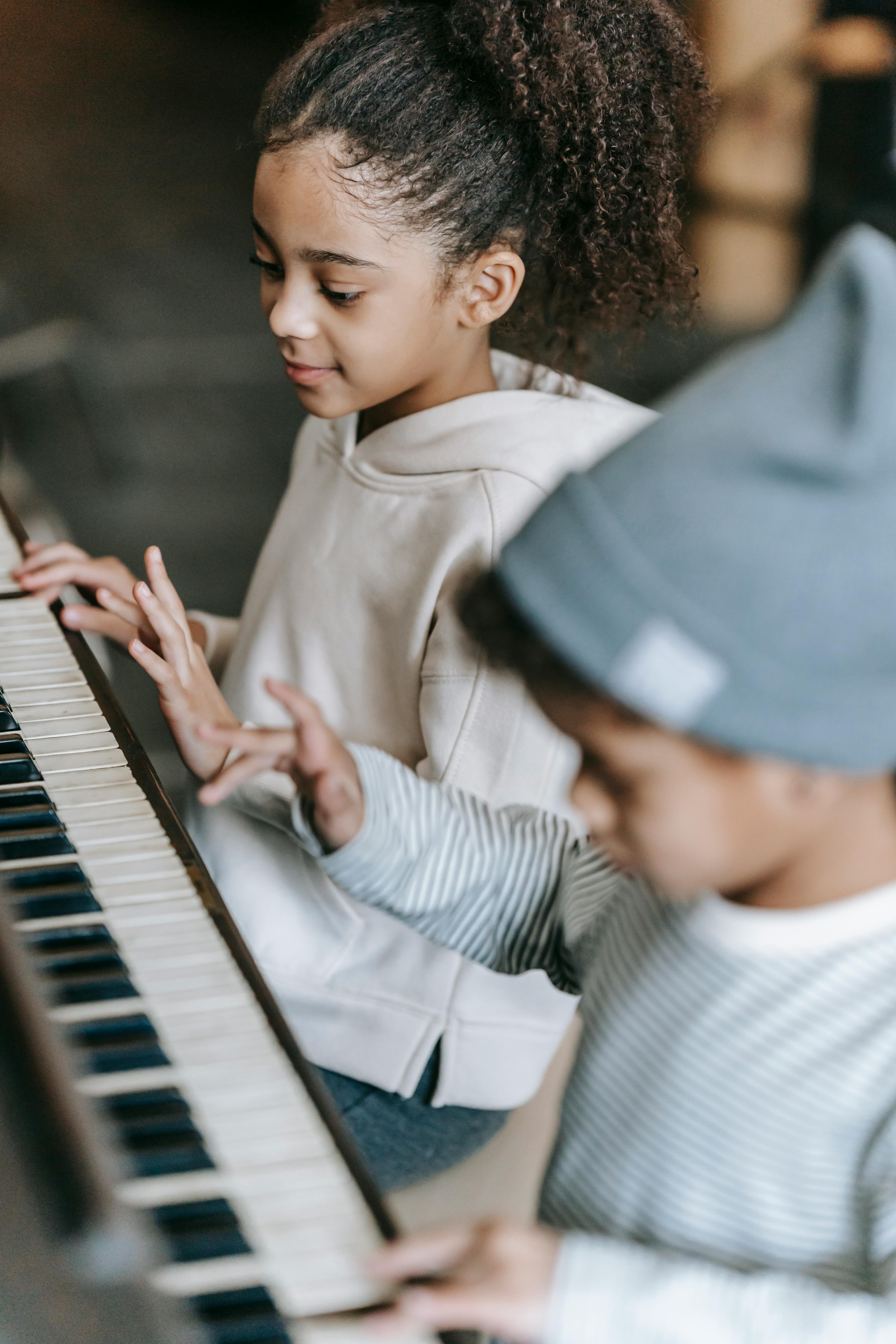 concentrated little black musicians playing piano together at home