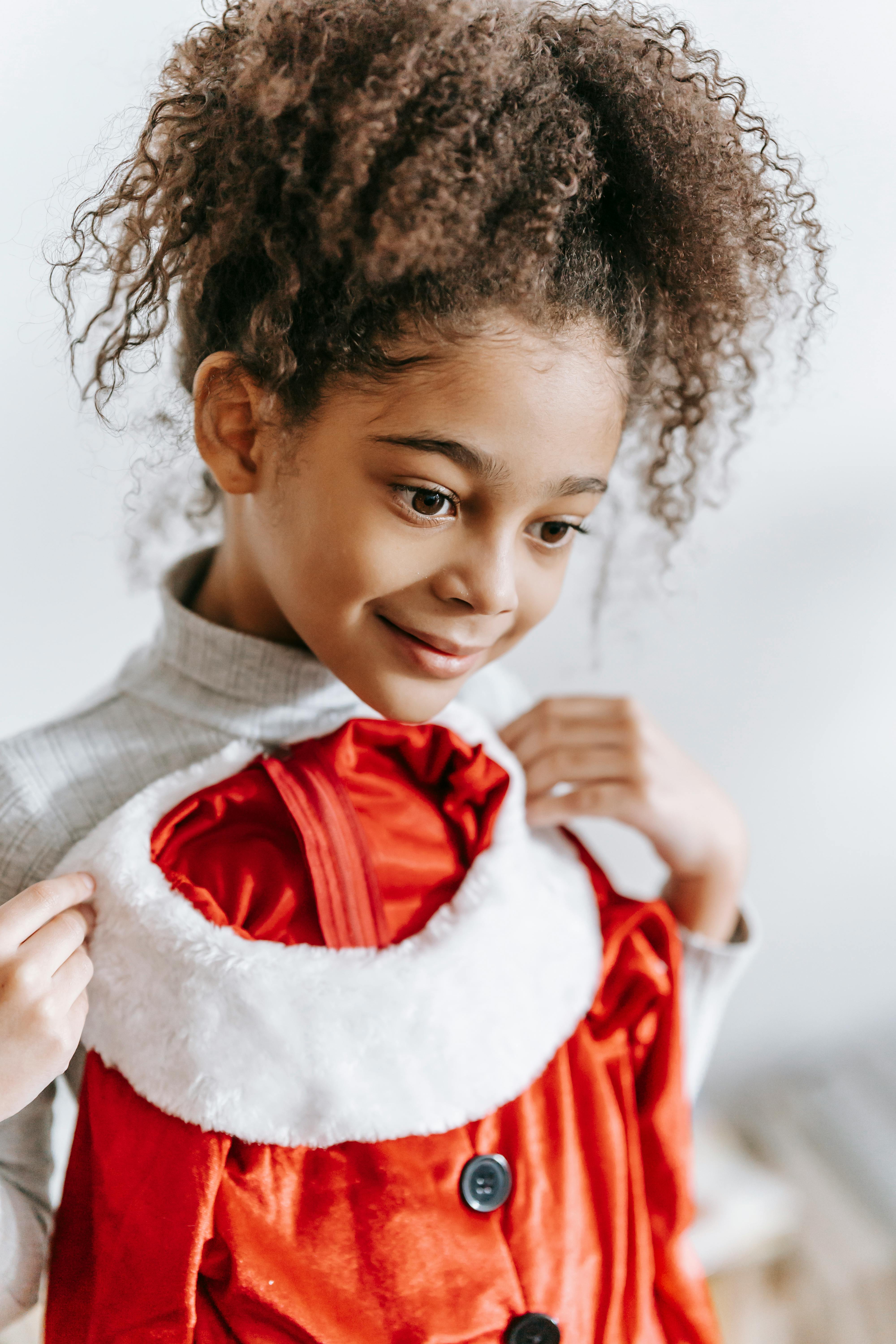 smiling black girl standing with christmas outfit in hand