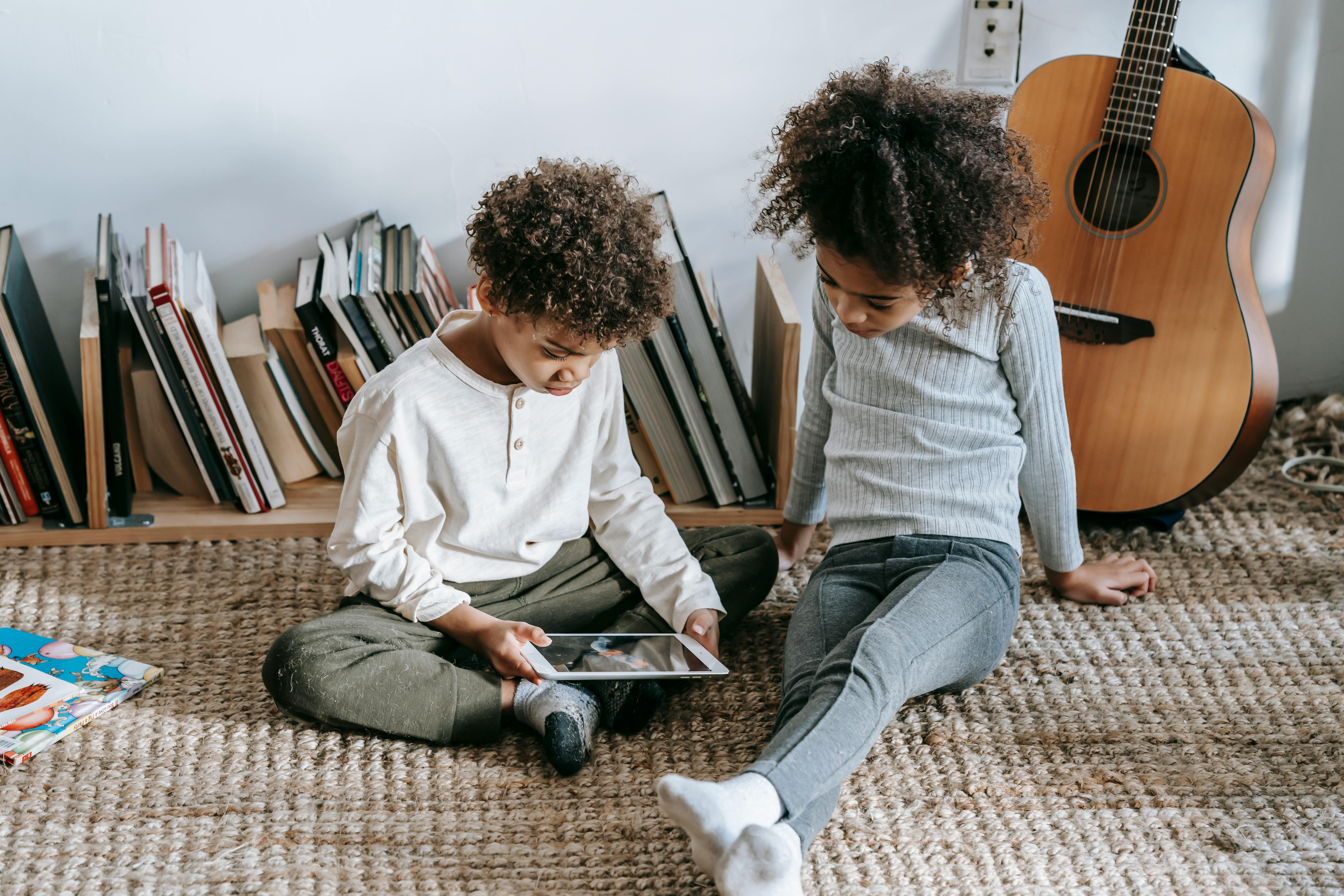 pensive black children browsing tablet while sitting in room at home