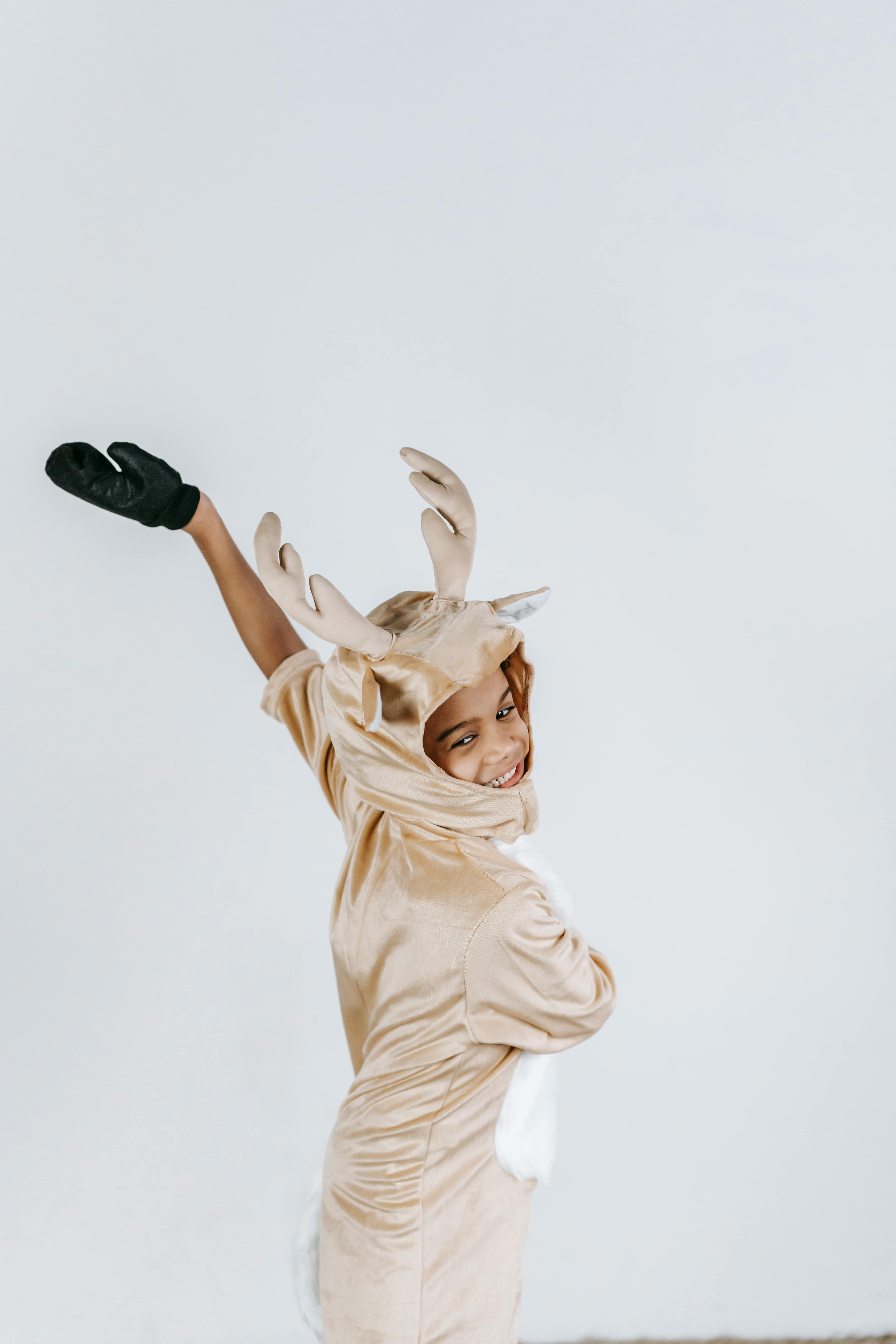 positive black boy in reindeer costume dancing