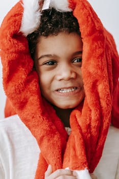 Smiling child in a red Santa hat brings joy and festive cheer to the holiday season.