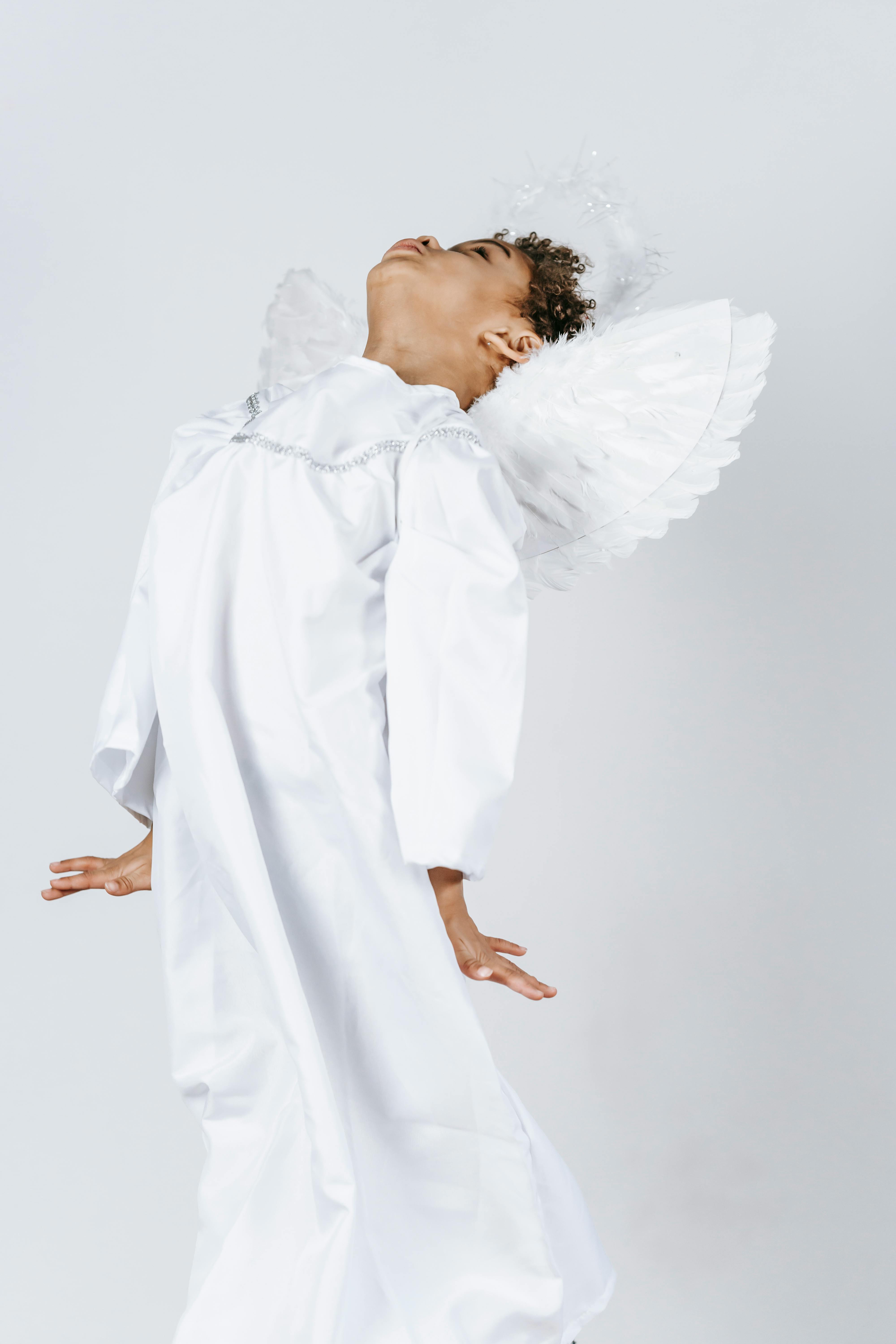 black boy in white costume with wings pretending angel