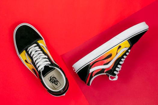Vibrant sneakers with flame design on a rich red background, highlighting modern footwear style.