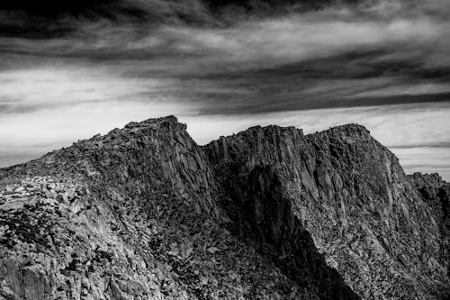 Grayscale Photography of the Rocky Mountains Under Cloudy Sky