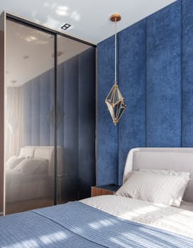 A stylish bedroom featuring a blue accent wall, contemporary lighting, and cozy bedding.