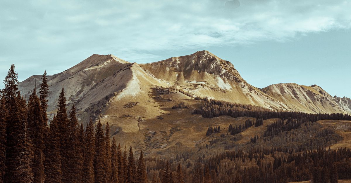 Breathtaking view of Crested Butte, Colorado's mountainous landscape with pine trees and dramatic sky.