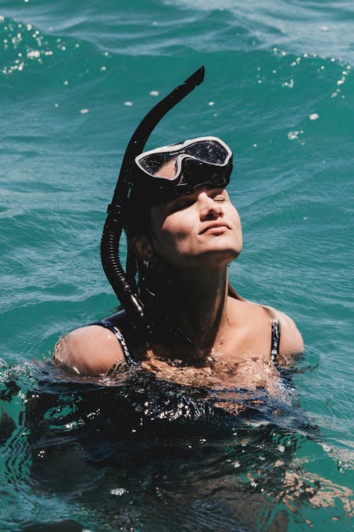 Free From above of happy female with eyes closed swimming in wavy water of sea on sunny day Stock Photo