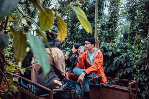 Men and woman sitting in a lush forest, enjoying a break with drinks in hand, creating a serene atmosphere.