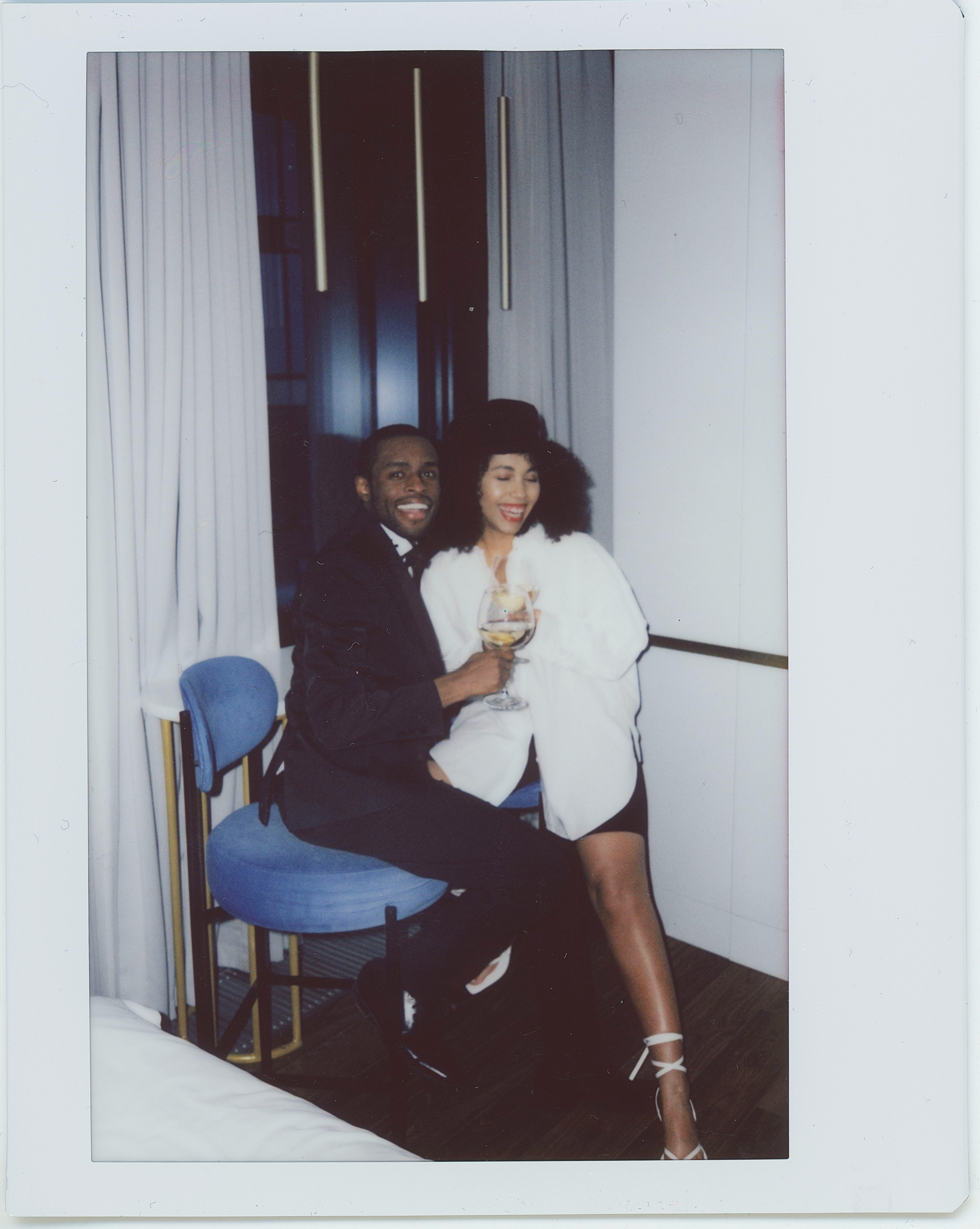 A well-dressed couple smiling and enjoying drinks indoors, capturing a happy moment.