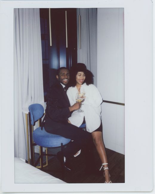 A well-dressed couple smiling and enjoying drinks indoors, capturing a happy moment.