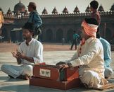 Man in White Thobe Sitting on Red Luggage