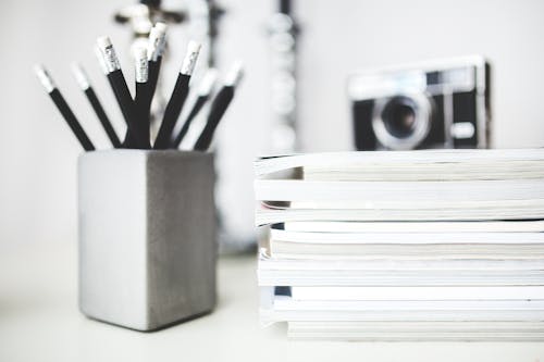 Stack of magazines & pencils in gray cup