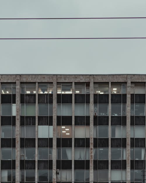 Exterior of aged building with concrete walls against cloudy gray sky in daylight