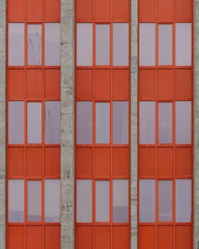 Exterior of residential building with orange walls and windows placed in city daytime