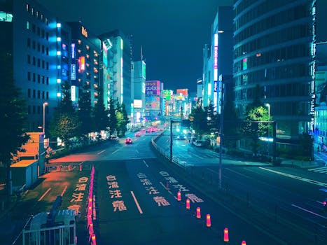 Vibrant Tokyo cityscape at night with neon lights and bustling streets, captured from above.