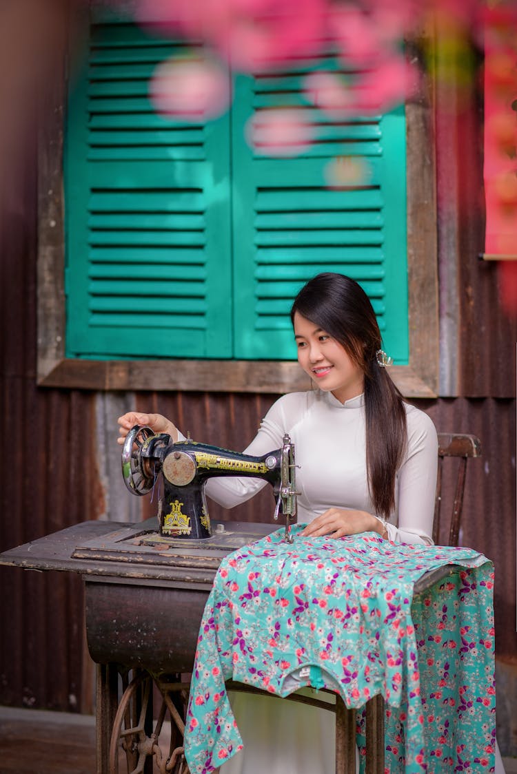 Young Woman Sewing On An Old Sewing Machine 