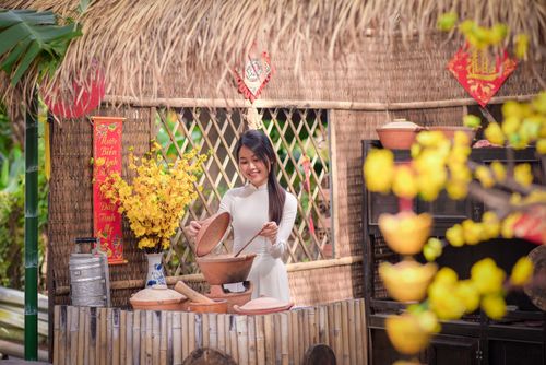 Free A joyful Asian woman in traditional clothes cooking with clay pots in a vibrant countryside setting. Stock Photo