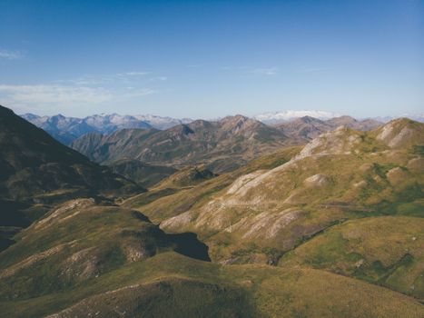 Spectacular scenery of massive rocky mountain range covered with grass against blue sky on sunny day