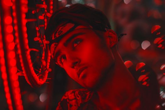 A striking portrait of a young man adorned with neon lights and vivid red tones, creating a mysterious, dreamlike effect.
