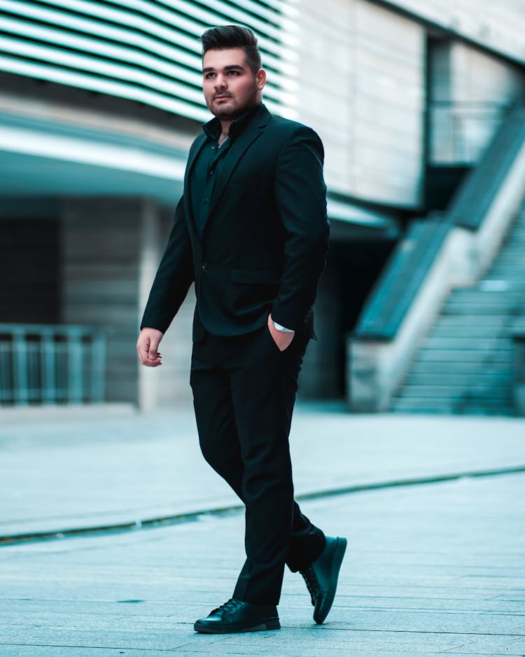 Man In Black Suit Walking With Hand In Pocket