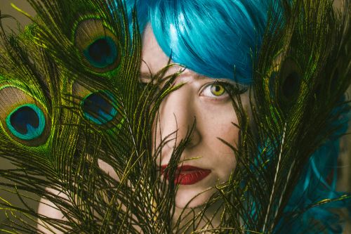 Free Striking portrait of a woman with vivid blue hair and peacock feathers, showcasing colorful and artistic expression. Stock Photo