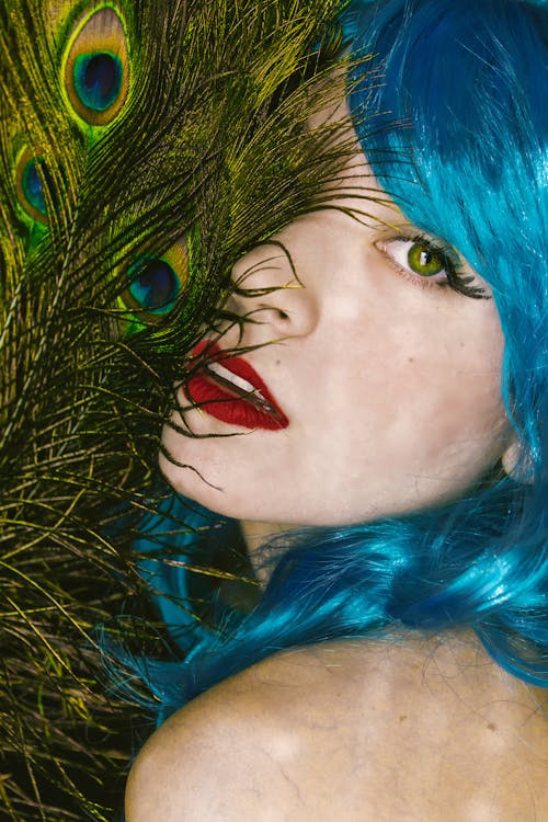 A Beautiful Woman with Blue Hair with Peacock Feathers on Her Face