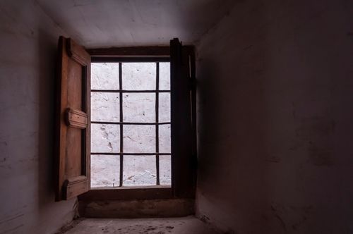 Free Old wooden window with metal grid in small room with shabby white wall in daytime Stock Photo