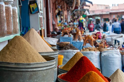 Metal containers with heaps of assorted aromatic colorful spices placed on stall in local outdoor market