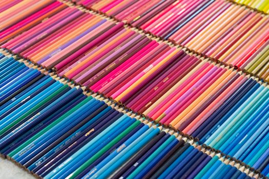 An artistic close-up of brightly colored pencils neatly arranged in rows, showcasing a wide color variety.