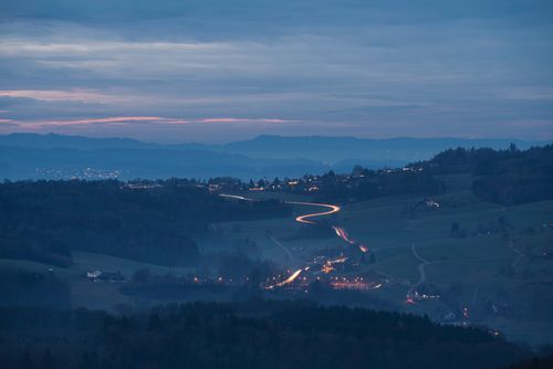 Free Blue hour aerial view of the Swiss countryside village with winding roads and twilight sky. Stock Photo