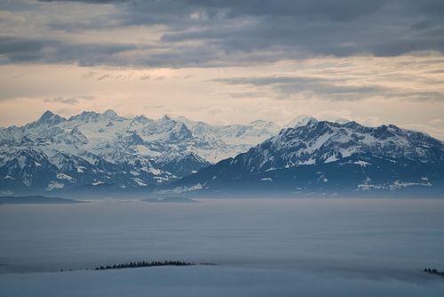 Free Captivating winter scene of snow-capped Swiss Alps under a cloudy sky at dawn. Stock Photo