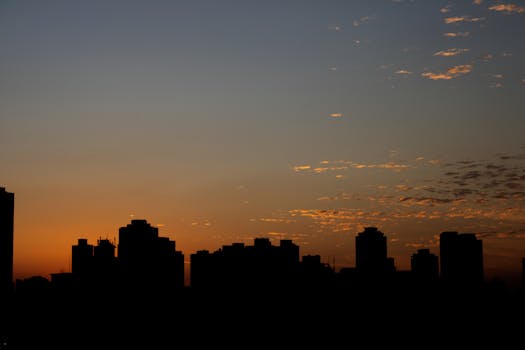 Silhouette of city buildings with a vibrant sunset sky backdrop.