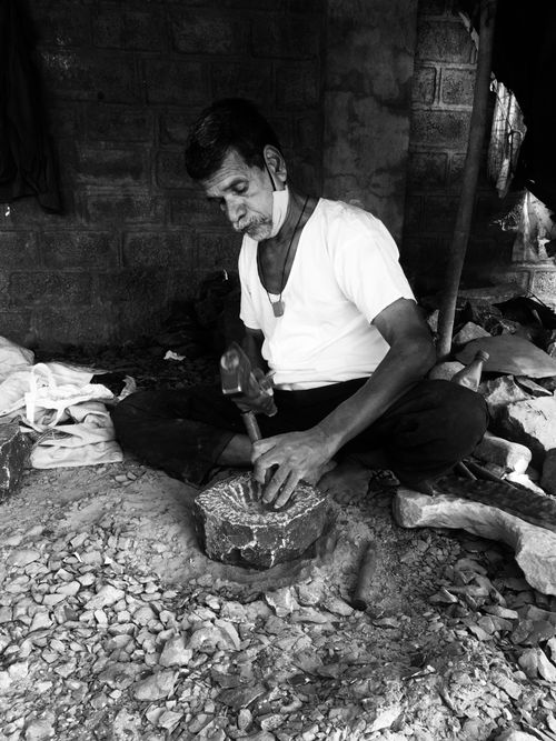 Free An elderly sculptor skillfully carves stone in a workshop, showcasing traditional craftsmanship. Stock Photo