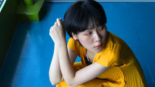 Free High-angle portrait of a stylish young woman in a yellow dress on a blue floor. Stock Photo