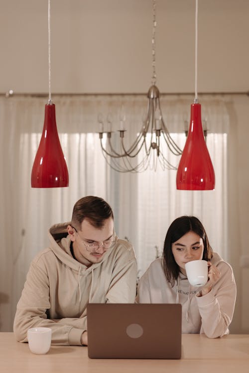 A Couple Having Coffee While Using a Laptop