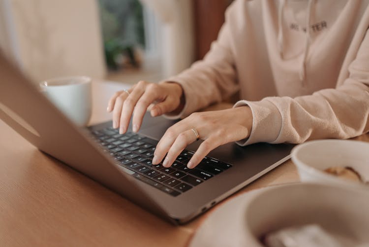 A Person Typing On A Laptop