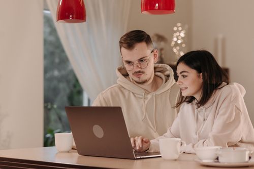 Free A couple in hoodies working from home on a laptop, drinking coffee. Stock Photo