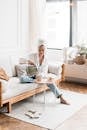 Woman with Towel Wrapped on Head Sitting on Couch Holding a Kettle