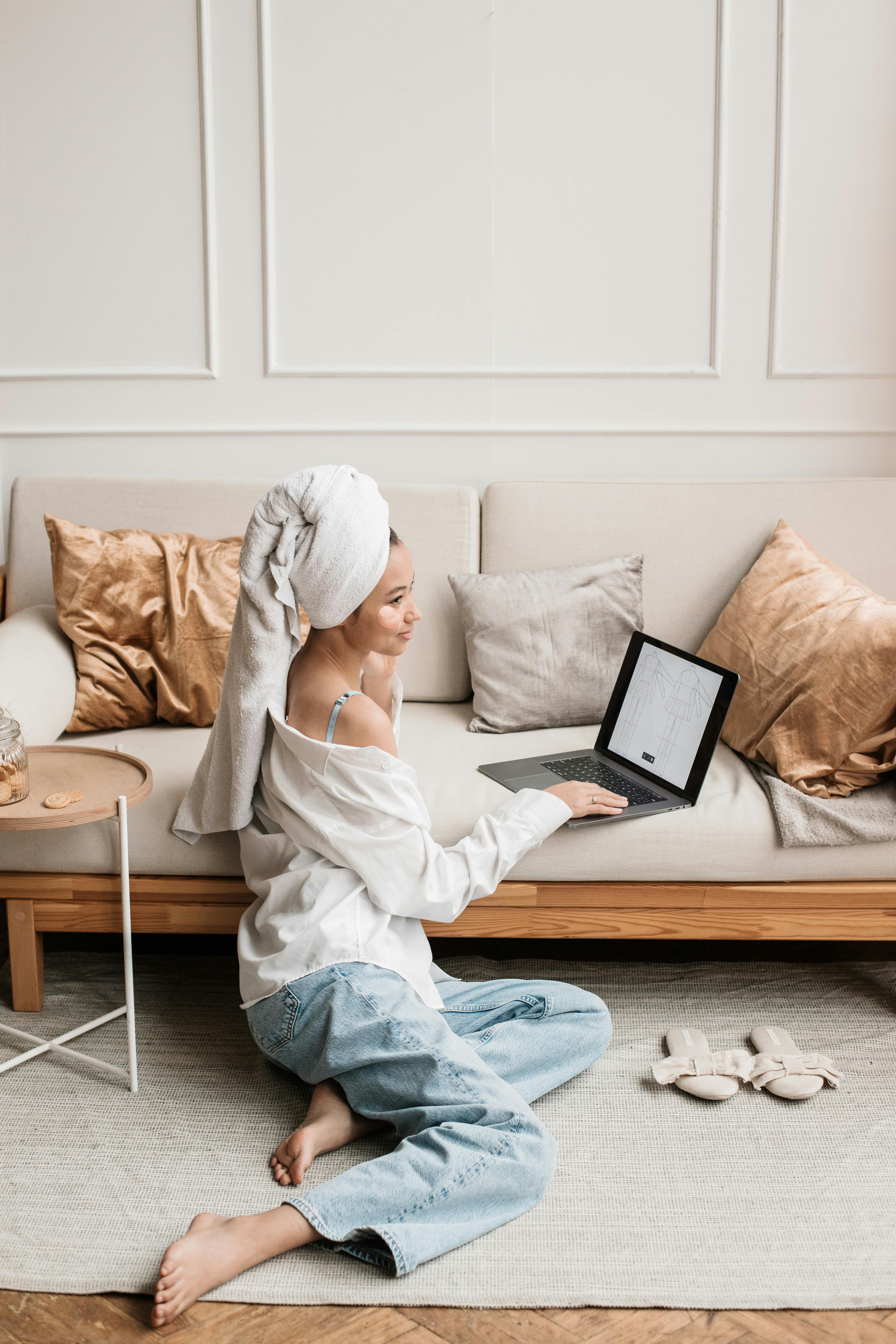 woman sitting on floor using laptop on couch