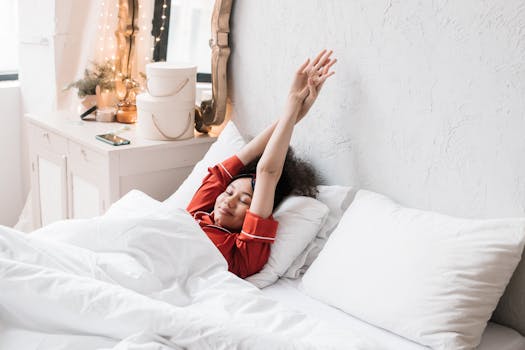 Woman in red pajamas stretching in a cozy, minimalist bedroom. Bright morning light enhances the serene scene.