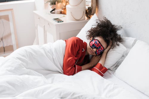 Woman Wearing Eye Mask Lying on White Bed