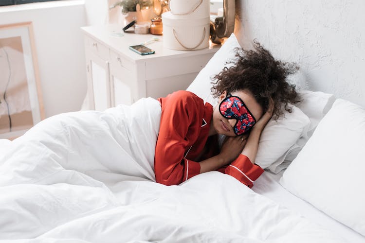 Woman Wearing Eye Mask Lying On White Bed