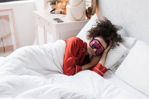 Free A woman in red pajamas sleeping with an eye mask in a bright, stylish bedroom. Stock Photo